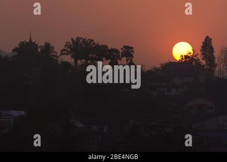 Beautiful Sunrise Behind a Temple and Palms at Laos, seen from Chiang Khong, Thailand, Asia Stock Photo