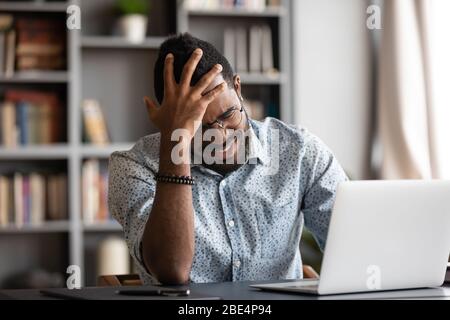 Stressed young african american man touching forehead, suffering from headache. Stock Photo