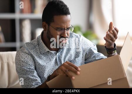 Young african american man feeling dissatisfied with received order. Stock Photo
