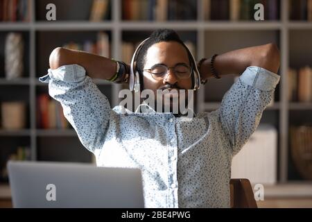 Peaceful young african american businessman relaxing listening to classis music. Stock Photo