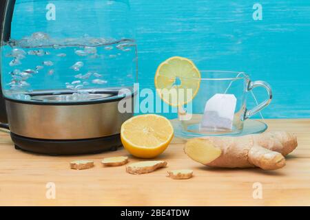 Electric kettle, cup, ginger, lemon on the table. Stock Photo