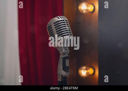 Retro microphone on stand on the background of red curtain. Music Stock Photo