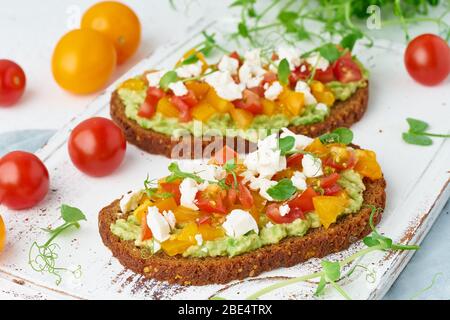 avocado toast with feta and tomatoes, smorrebrod with ricotta, closeup Stock Photo