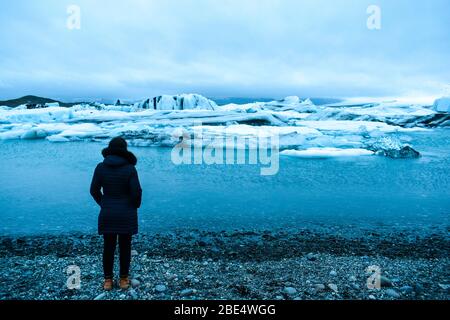 A female traveler looking at the Jokulsarlon Glacial Lagoon Stock Photo