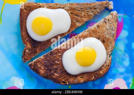M&S Fried Eggs decorated solid white chocolate ready for Easter set on toast on colourful plate - eggs on toast concept - breakfast egg Stock Photo