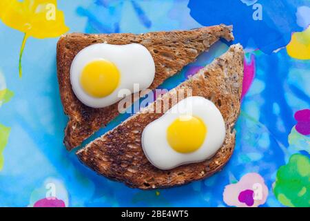M&S Fried Eggs decorated solid white chocolate ready for Easter set on toast on colourful plate - eggs on toast concept - breakfast egg Stock Photo