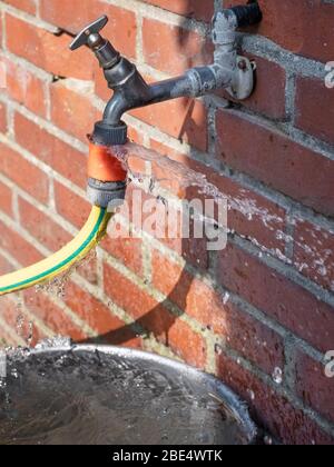 Defective faucet. leaking hose on an outside tap Stock Photo - Alamy