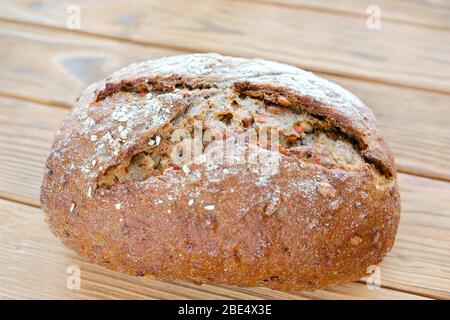Carrot bread on a wooden background. Uncut piece of bread. Home-made, environmentally friendly product. Stock Photo