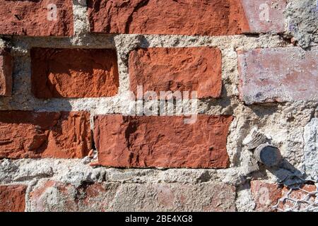 red brick wall detail with damaged plaster Stock Photo
