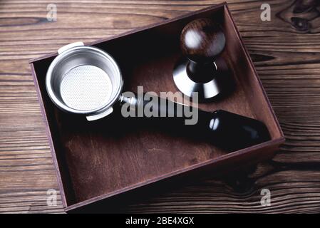 Accessories for making coffee, coffee horn and tamper in a wooden box on a natural wooden background close-up Stock Photo