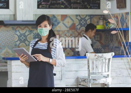 Portrait of waitress using digital tablet and wear face masks Stock Photo