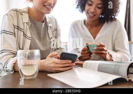 Cropped image of two happy young women friends sitting at the cafe, having coffee Stock Photo