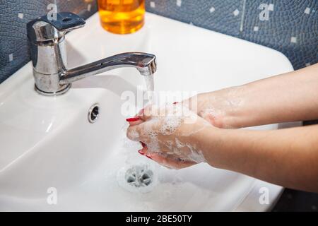 woman washes hands with soap in a washroom. coronavirus quarantine. hands closeup