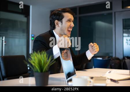 Asian businessmen Success and winning concept - happy team with raised up hands celebrating the breakthrough and achievements Stock Photo