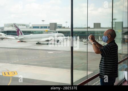28.03.2020, Singapore, Republic of Singapore, Asia - A man at the viewing mall of Terminal 1 uses his smartphone to film aeroplanes on the apron. Stock Photo