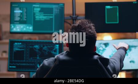Back view dangerous and wanted cyber criminal searching on government database. Stock Photo