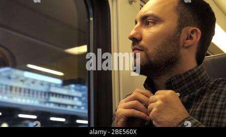 Young urban casual businessman buttons up shirt in a train or subway. Stock Photo