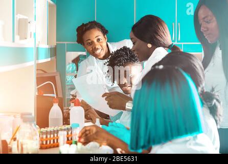 African medics, technical assistants, scientists, young women work in research laboratory, medical test lab. Quality control of various substances, in Stock Photo