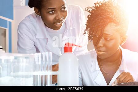 Two African medics, technical assistants, scientists, young women work in research laboratory, medical test lab. Quality control of water samples for Stock Photo