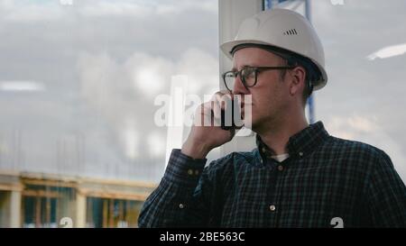 Engineer making call while standing at construction area. Stock Photo