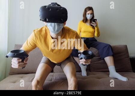 Stay at home and play. A guy and a girl are passionate about digital space. The guy plays virtual games.  Stock Photo