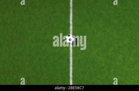 Football or soccer ball on a white center line on green turf on a sports field viewed from above with copy space in a conceptual image Stock Photo