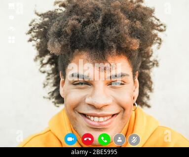 Mixed race young man portrait - Happy afro guy smiling in front of camera - Millennial generation and multi ethnicity concept - Focus on face Stock Photo