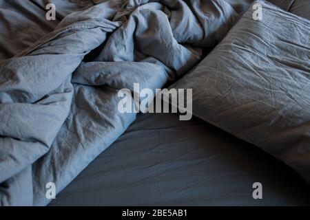 A gray cotton sheet and blankets with pillows on the bed Stock Photo