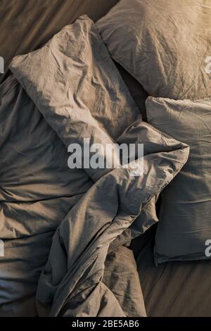 A gray cotton sheet and blankets with pillows on the bed Stock Photo