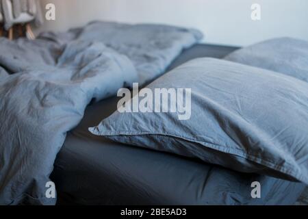 Closeup of gray pillows and blankets with a sheet on the bed Stock Photo