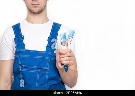 The guy holds brushes in his hands. The guy paints the walls Stock Photo