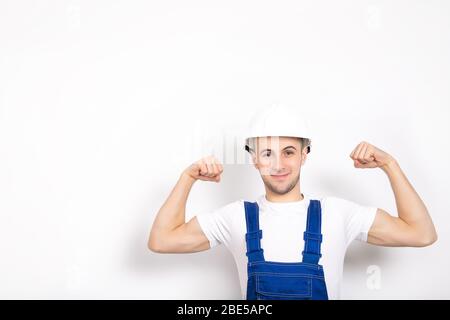 Cheerful strong guy in a helmet on a white background. Place for text Stock Photo