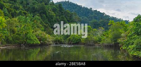 Pristine vibrant jungle river surrounded by lush hills in distance seen in West Sumatra, Indonesia Stock Photo