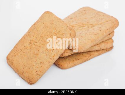 Stack of square organic crispy wheat and five grain salty crackers on white background. Stock Photo
