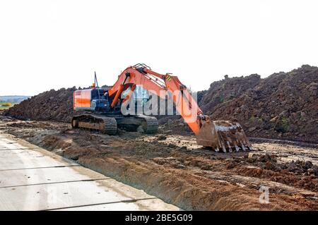 Crawler excavator at a construction site. Excavator with a bucket lowered down. Building background. Stock Photo