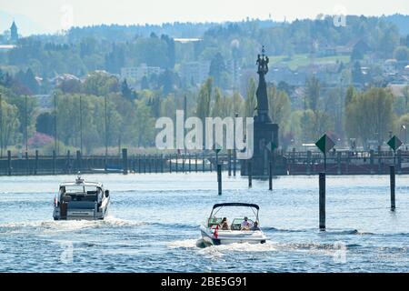 Konstanz, Germany. 12th Apr, 2020. Two motorboats from Switzerland are heading towards Kreuzlingen, while in the background the landmark of Constance, the rotating, oversized stone figure Imperia, can be seen. Credit: Felix Kästle/dpa/Alamy Live News Stock Photo