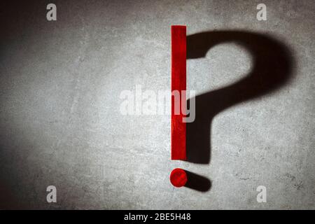 exclamation point lit in spotlight changes into a question mark from shadow. Question mark, exclamation point concept question or solution Stock Photo