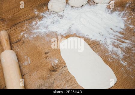 Rolling pin, dough and flour on the table. The process of making homemade cakes. Homemade baking. Cooking from home dough. Stock Photo