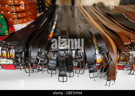 Shallow depth of field (selective focus) image with many types of leather belts on sale in a Romanian traditional market. Stock Photo
