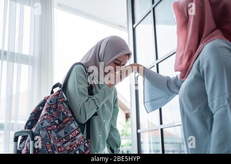 asian young girl kisses her mother's hand when returning home, an Asian Muslim family Stock Photo