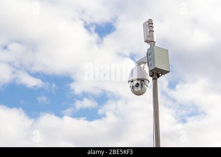 Security Camera on a blue sky background. Surveillance camera for guarding territory. Security of private property. Stock Photo