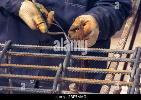 Assembly of reinforcing bars for pouring concrete. Construction worker fabricating steel reinforcement bars. Preparation for concrete work.Wire mounti Stock Photo