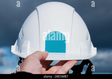 White construction helmet of the foreman against the blue sky. Personal protective equipment at the construction site. Headpiece made of durable plati Stock Photo