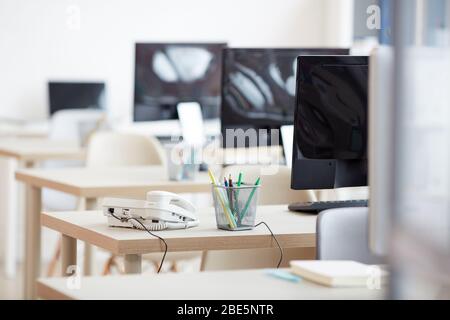 Background image of empty office workplaces in row with focus on wired telephone on desk in call center, copy space Stock Photo