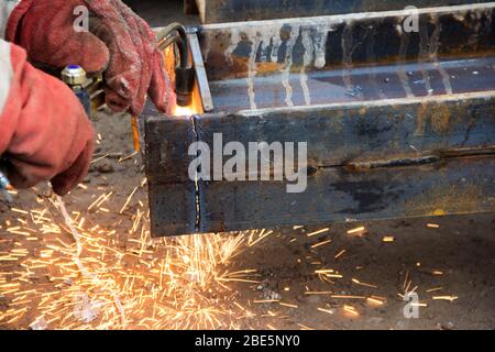 Cutting a steel beam with a gas torch. Industrial metal cutting. The process of preparing a steel beam for installation. Stock Photo