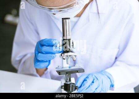 Medical Research asian Scientist Working With Microscope Doing Research Making Scientific Experiment, Works in a Bright Modern Laboratory Stock Photo