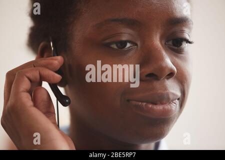 Close up portrait of African-American woman wearing headset and talking to customer while working in support service call center, copy space Stock Photo