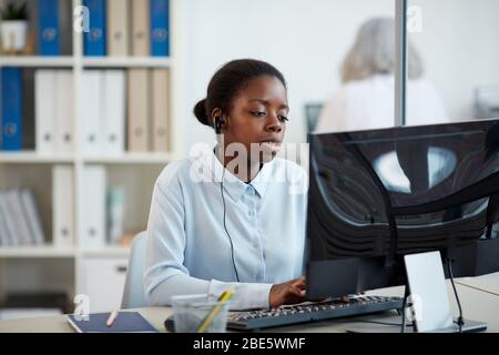 Portrait of African-American woman wearing headset while working as call center operator in office interior, copy space Stock Photo