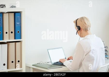 Back view portrait of modern businesswoman wearing headset while working from home, copy space Stock Photo