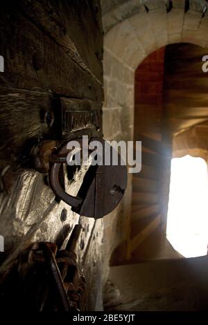 Padlock on an ancient castle cell door with natural light streaming in through a separate doorway Stock Photo